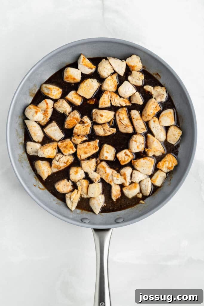 Chicken pieces in a skillet with homemade teriyaki sauce before simmering