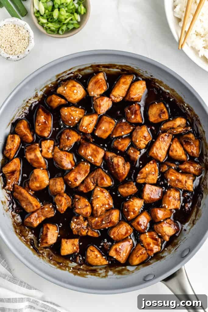 Chicken Teriyaki in a skillet topped with sesame seeds and green onions