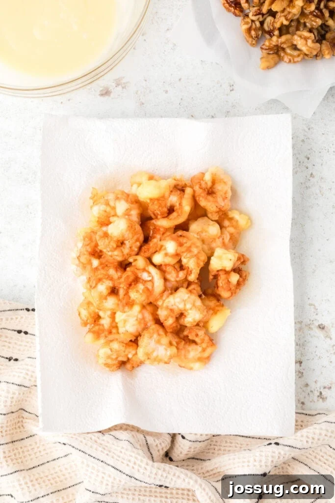 Crispy Honey Walnut Shrimp Recipe: Restaurant-Style at Home 15 Fried shrimp draining on paper towels for homemade Honey Walnut Shrimp