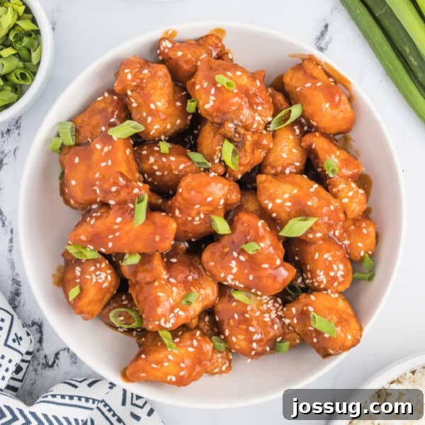 Homemade Hibachi Chicken: Restaurant-Style Recipe You’ll Love 19 Square crop of a bowl filled with saucy sesame chicken, garnished with sesame seeds and green onions, styled with rice and fresh garnishes on the side.