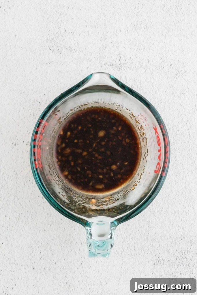 Homemade Hibachi Chicken: Restaurant-Style Recipe You’ll Love 5 Close-up of homemade hibachi chicken sauce made with soy sauce, garlic, ginger, sesame oil, and brown sugar in a glass measuring cup.