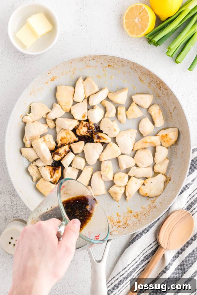 Homemade Hibachi Chicken: Restaurant-Style Recipe You’ll Love 8 Pouring homemade hibachi sauce over cooked chicken pieces in a skillet for an easy Hibachi Chicken recipe.