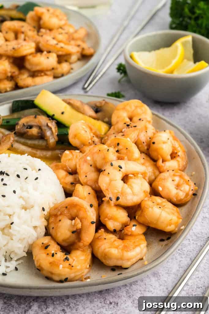 Copycat Hibachi Shrimp Recipe: Restaurant-Style at Home 2 Plate of Hibachi Shrimp with white rice and hibachi vegetables, served with lemon wedges on the side.