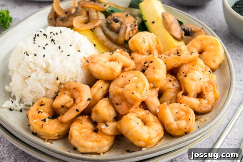 Copycat Hibachi Shrimp Recipe: Restaurant-Style at Home 4 Close-up of Hibachi Shrimp served with white rice, zucchini, mushrooms, and onions, garnished with sesame seeds.