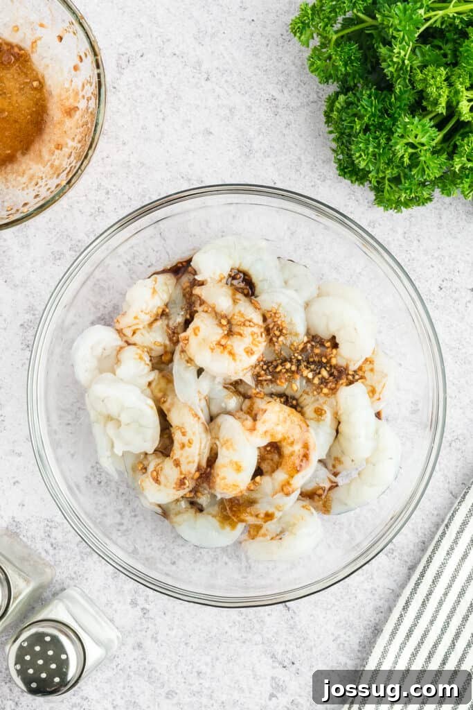 Copycat Hibachi Shrimp Recipe: Restaurant-Style at Home 7 Raw shrimp in a glass bowl topped with Hibachi Shrimp marinade ingredients.