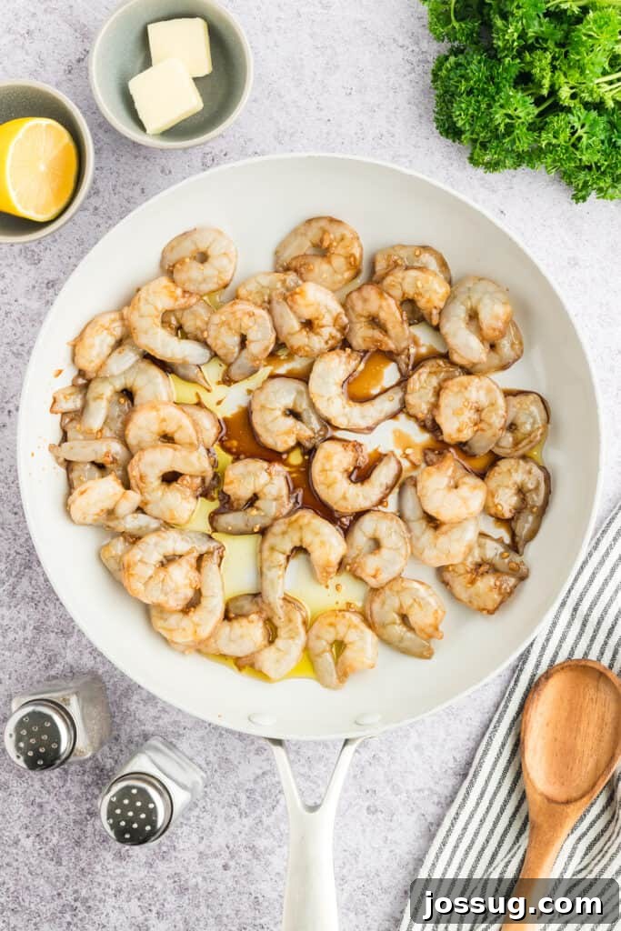 Copycat Hibachi Shrimp Recipe: Restaurant-Style at Home 9 Marinated shrimp and butter added to a white skillet before cooking.