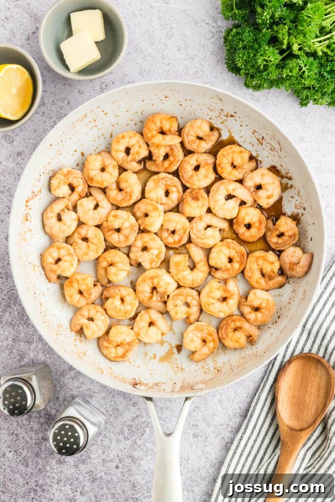 Copycat Hibachi Shrimp Recipe: Restaurant-Style at Home 10 Hibachi Shrimp cooking in a white skillet with sauce.