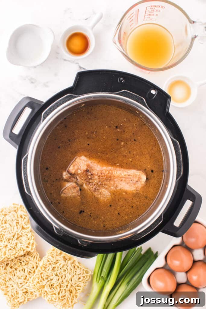 Instant Pot Pork Ramen Recipe: Homemade Broth in 30 Minutes 8 Pork shoulder simmering in broth inside an Instant Pot with ramen noodles, eggs, bean sprouts, nori, and green onions around the pot