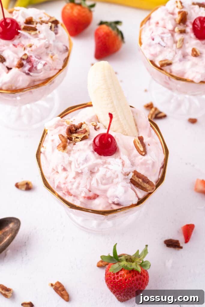 Three dessert dishes filled with Banana Split Salad and garnished with bananas, pecans, coconut, and maraschino cherries.