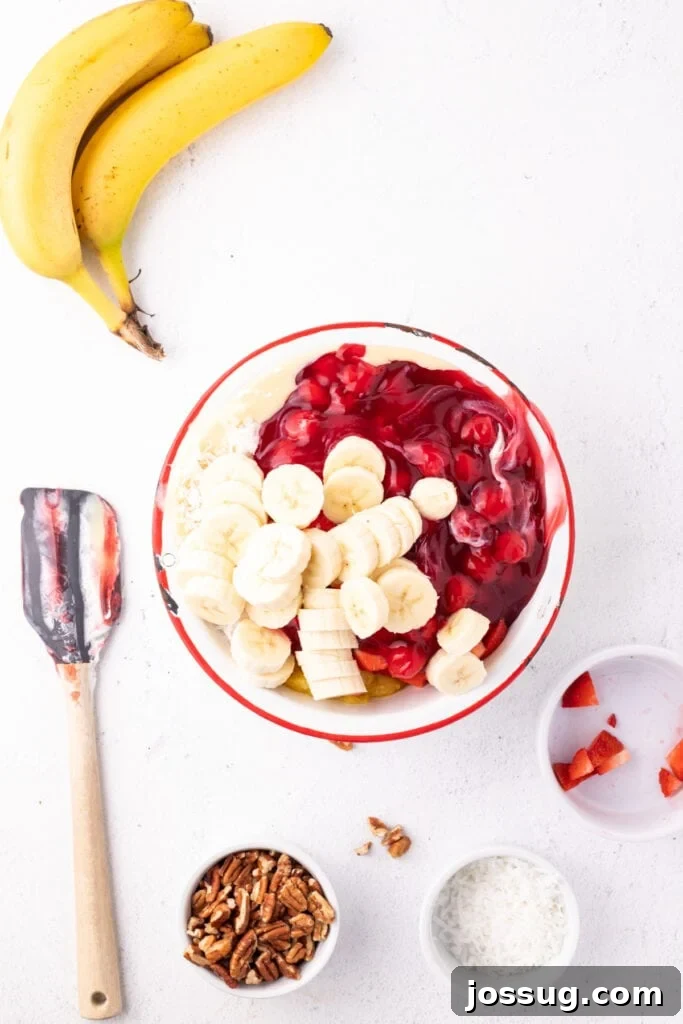 Sliced bananas added to a bowl of Banana Split Salad ingredients before mixing.