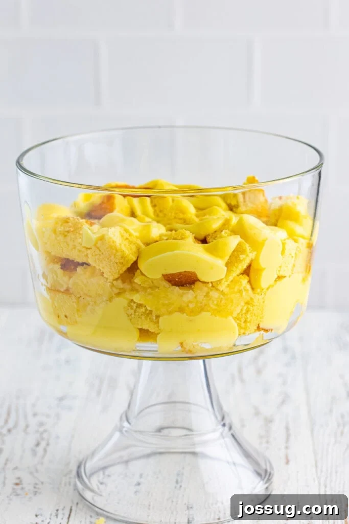 Decadent Banana Split Trifle Recipe with Layers of Cream and Fruit 11 Second layer of vanilla pudding spooned over cake cubes in a clear trifle bowl for Banana Split Trifle.