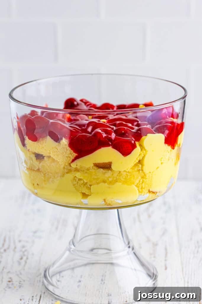 Decadent Banana Split Trifle Recipe with Layers of Cream and Fruit 12 Layer of strawberry pie filling added to the trifle bowl over cake and pudding for Banana Split Trifle.