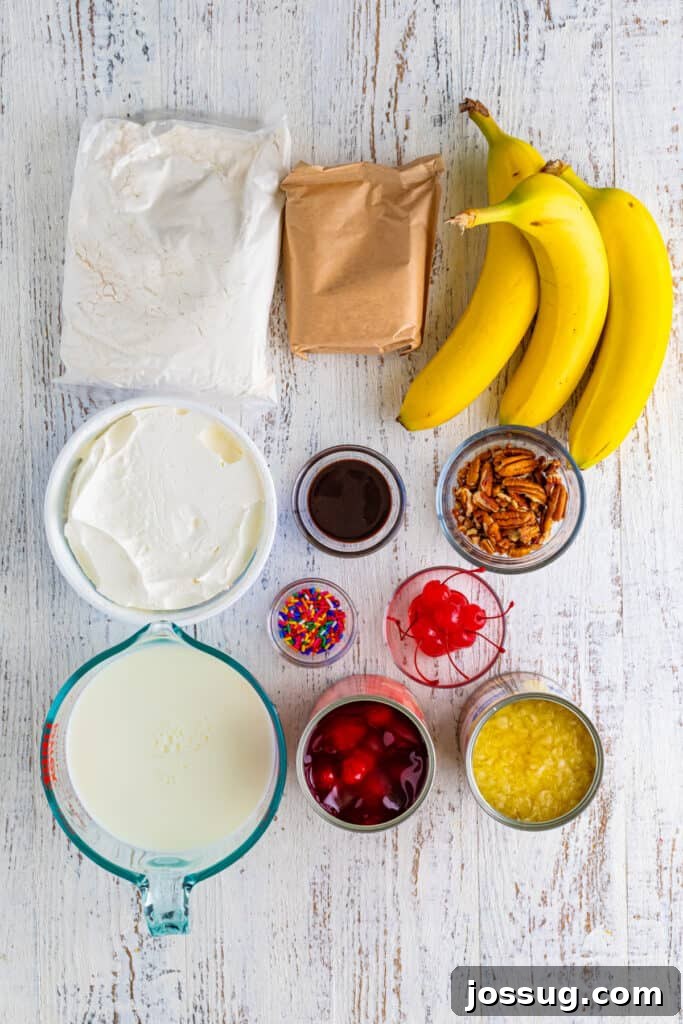 Decadent Banana Split Trifle Recipe with Layers of Cream and Fruit 3 Ingredients for Banana Split Trifle arranged on a white wood surface, including yellow cake mix, vanilla pudding mix, whole milk, bananas, whipped topping, crushed pineapple, strawberry pie filling, chocolate sauce, pecans, rainbow sprinkles, and maraschino cherries.