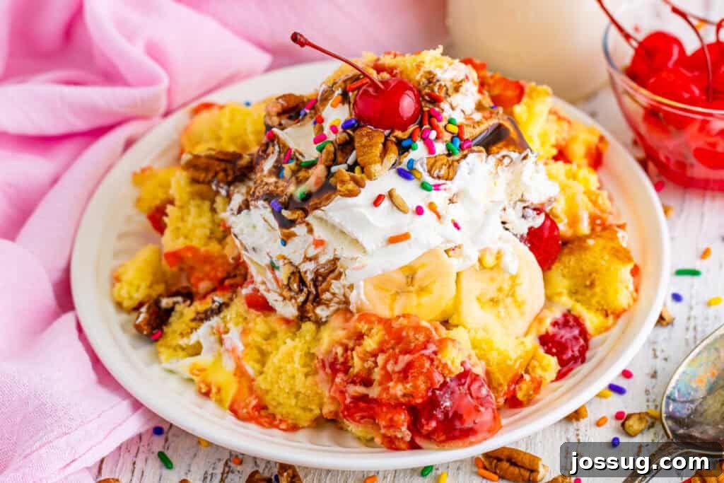 Decadent Banana Split Trifle Recipe with Layers of Cream and Fruit 4 Close-up of a plated serving of Banana Split Trifle topped with whipped topping, chocolate sauce, pecans, rainbow sprinkles, and a maraschino cherry.