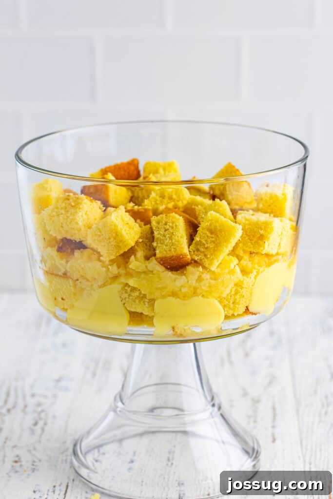 Decadent Banana Split Trifle Recipe with Layers of Cream and Fruit 10 Additional layer of cubed yellow cake added to the trifle bowl over pineapple and pudding for Banana Split Trifle.