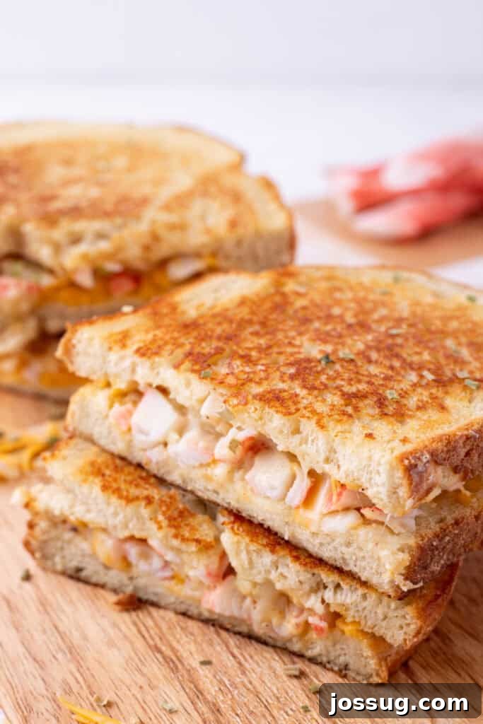 Cheesy Crab Melt: Seafood Grilled Cheese Sandwich Recipe 2 Stacked halves of Cheesy Crab Melt sandwiches on a wooden cutting board