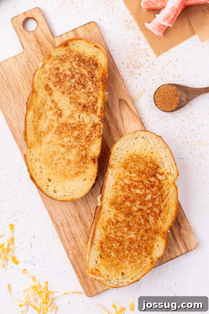 Cheesy Crab Melt: Seafood Grilled Cheese Sandwich Recipe 13 Two golden brown Cheesy Crab Melt sandwiches on a wooden cutting board