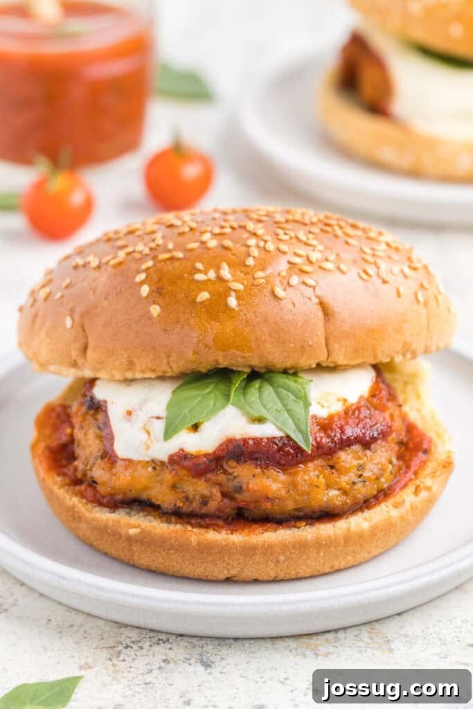 Crispy Chicken Parmesan Burgers with Marinara and Mozzarella 2 Chicken Parm Burger topped with marinara sauce, melted mozzarella, and basil on a sesame seed bun
