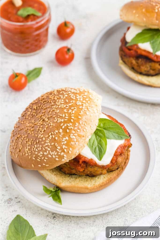 Crispy Chicken Parmesan Burgers with Marinara and Mozzarella 13 Chicken Parm Burger topped with mozzarella cheese and basil on a sesame seed bun