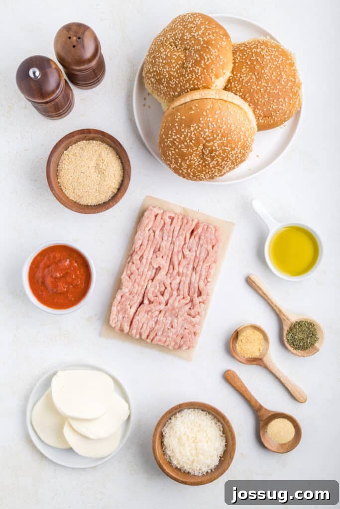 Crispy Chicken Parmesan Burgers with Marinara and Mozzarella 3 Ingredients for Chicken Parm Burgers arranged on a countertop including ground chicken, marinara sauce, breadcrumbs, Parmesan cheese, mozzarella, seasonings, olive oil, and burger buns