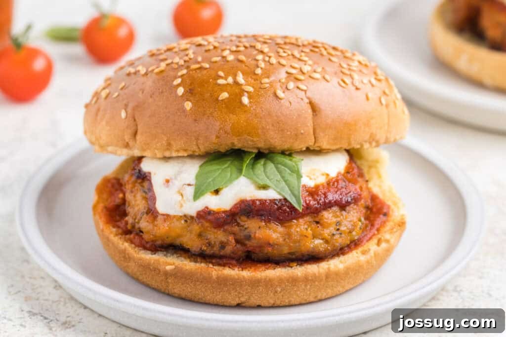 Crispy Chicken Parmesan Burgers with Marinara and Mozzarella 4 Close-up of a Chicken Parm Burger with marinara sauce, melted mozzarella, and basil on a sesame seed bun