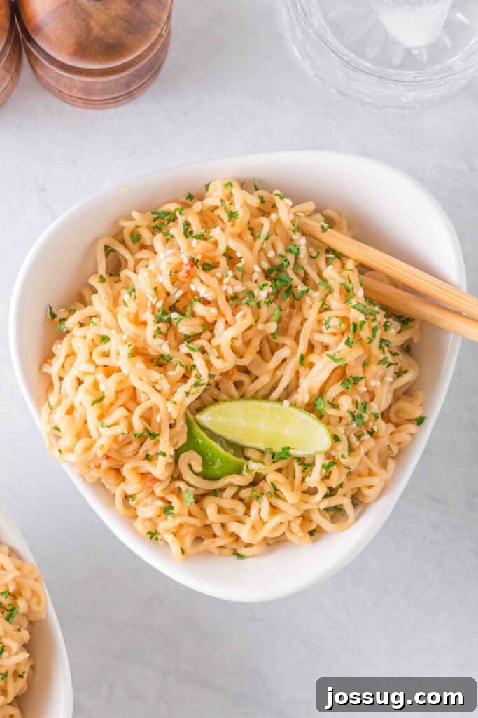 Creamy Peanut Butter Ramen Noodles Recipe in 10 Minutes 2 Overhead view of creamy Peanut Butter Ramen Noodles garnished with sesame seeds, parsley, and fresh lime.