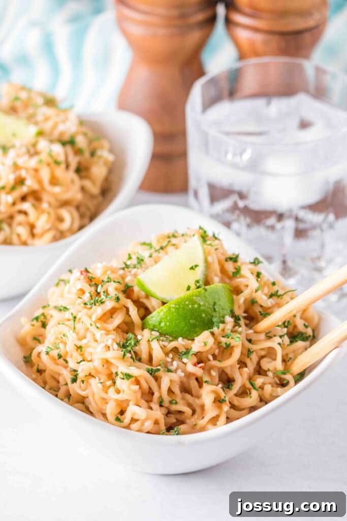 Creamy Peanut Butter Ramen Noodles Recipe in 10 Minutes 7 Bowl of creamy Peanut Butter Ramen Noodles garnished with sesame seeds, parsley, and lime wedges.