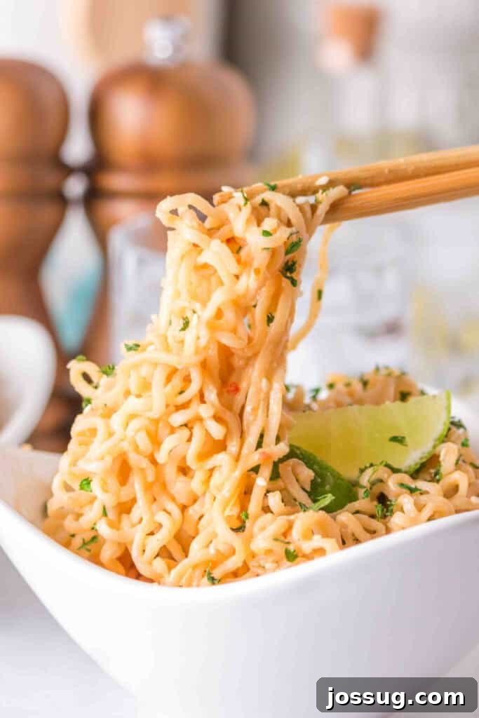 Creamy Peanut Butter Ramen Noodles Recipe in 10 Minutes 9 Close-up of creamy Peanut Butter Ramen Noodles topped with sesame seeds, parsley, and a fresh lime wedge.