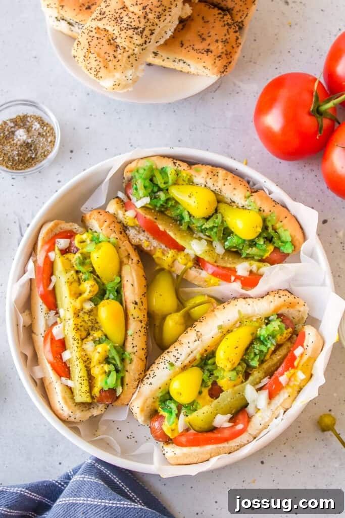 Three authentic Chicago Hot Dogs with sport peppers, relish, tomatoes, onions, mustard, pickles, and celery salt