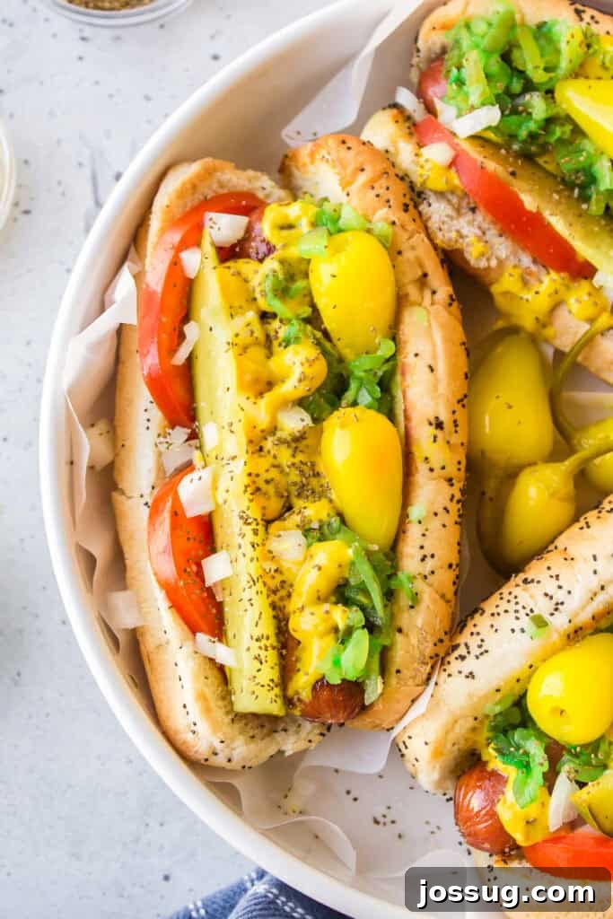 Close-up of an authentic Chicago Hot Dog loaded with pickle spear, tomato, onion, sport peppers, relish, mustard, and celery salt