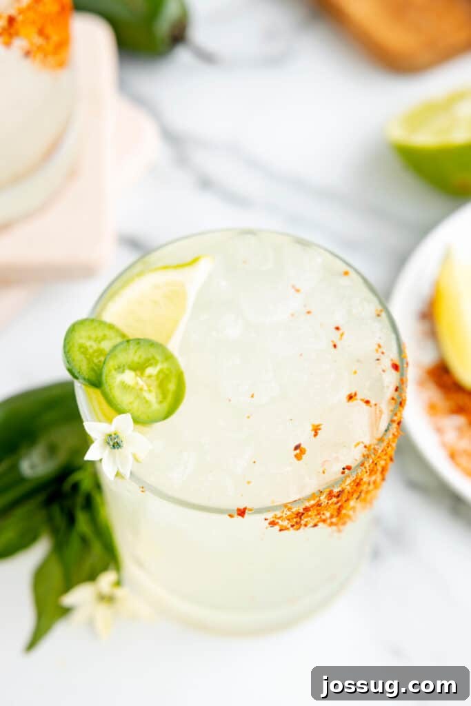 Jalapeño Margarita: Spicy Lime Cocktail Recipe 2 Spicy margarita recipe served over ice with fresh jalapeño slices, a lime wedge, and a Tajín rim