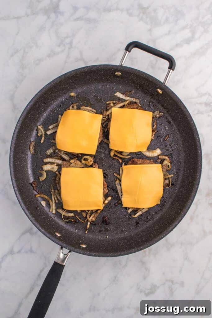 Oklahoma Onion Smash Burger Recipe with Caramelized Onions 8 American cheese melting over Oklahoma Onion Burgers.