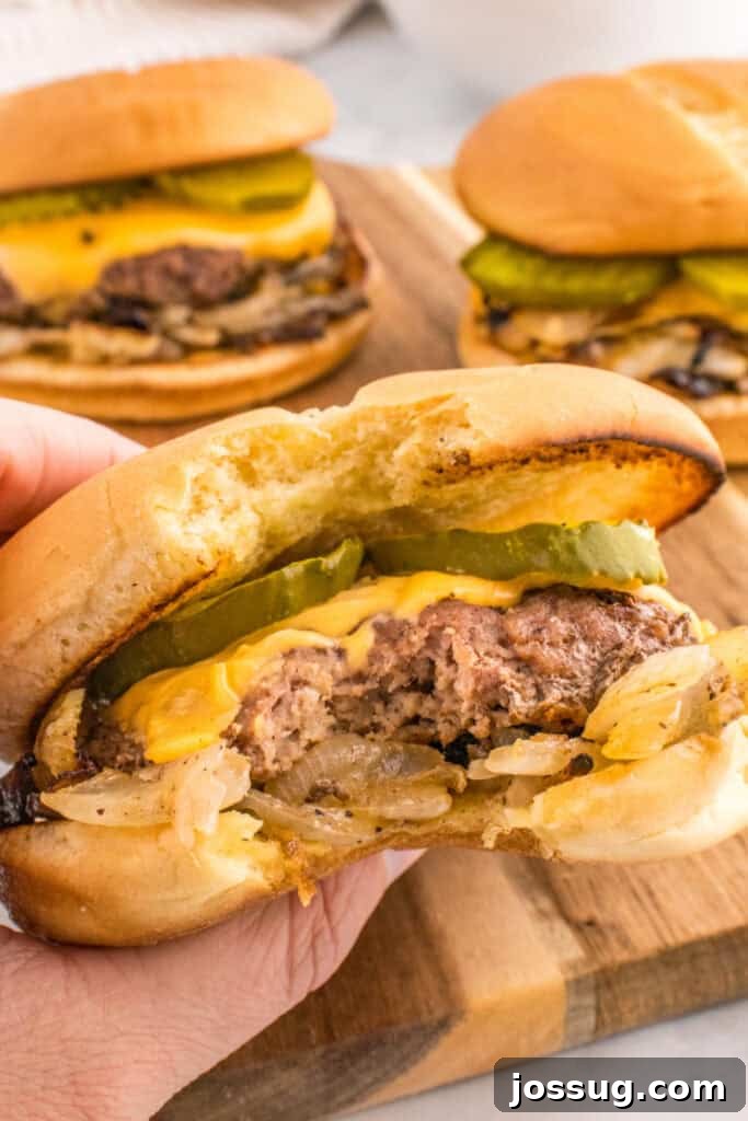 Oklahoma Onion Smash Burger Recipe with Caramelized Onions 9 Bite taken from an Oklahoma Onion Burger showing the juicy beef and caramelized onions.