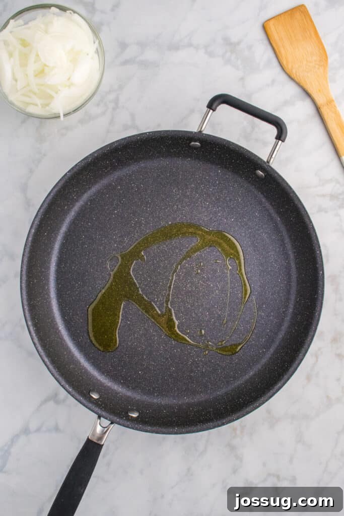 Oklahoma Onion Smash Burger Recipe with Caramelized Onions 5 Oil heating in a large skillet for making Oklahoma Onion Burgers.