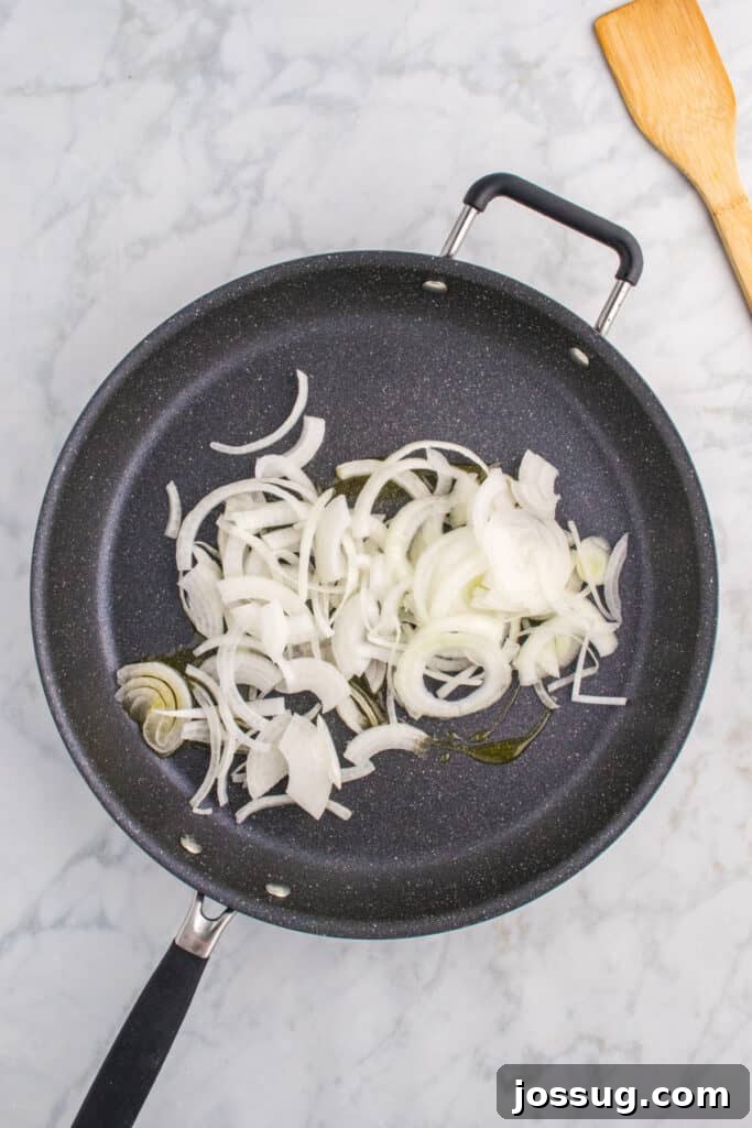 Oklahoma Onion Smash Burger Recipe with Caramelized Onions 6 Thinly sliced onions cooking in a skillet.