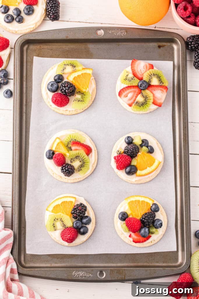 Fruit Pizza Cookies: Sugar Cookie Dessert with Fresh Fruit 15 Fruit Pizza Cookies decorated with colorful fresh fruit on a baking sheet.