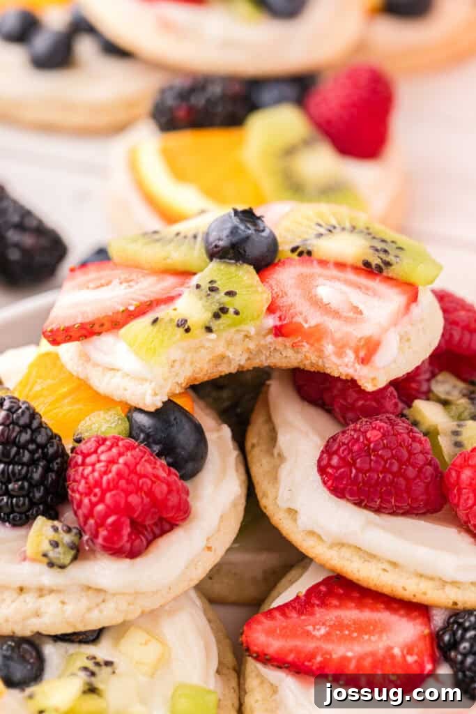 Fruit Pizza Cookies: Sugar Cookie Dessert with Fresh Fruit 17 Bitten Fruit Pizza Cookie topped with cream cheese frosting, strawberries, kiwi, and blueberries, showing the soft sugar cookie center.