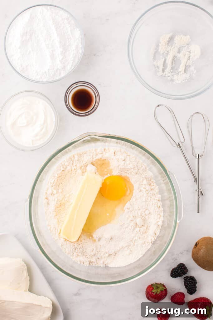 Fruit Pizza Cookies: Sugar Cookie Dessert with Fresh Fruit 5 Sugar cookie mix, butter, egg, sour cream, and vanilla being added to a mixing bowl.