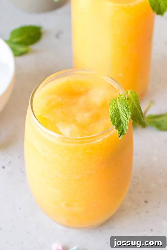 Frozen Peach Bellini Cocktail Recipe for Summer 9 Refreshing frozen peach cocktail topped with fresh mint for a summer brunch drink.