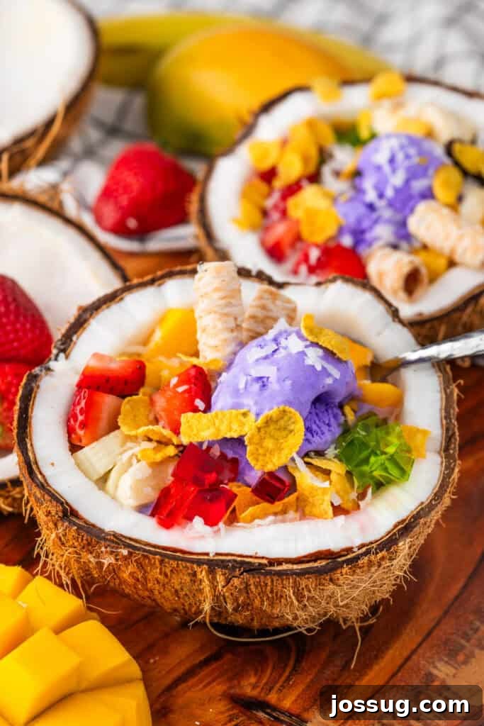 Halo-Halo: Authentic Filipino Shaved Ice Recipe 2 Halo Halo recipe served in a fresh coconut shell with ube ice cream, mango, strawberries, colorful gelatin, boba, and wafer cookies.