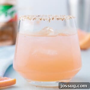 Close-up of a refreshing Paloma Cocktail served over ice with a Tajín rim.