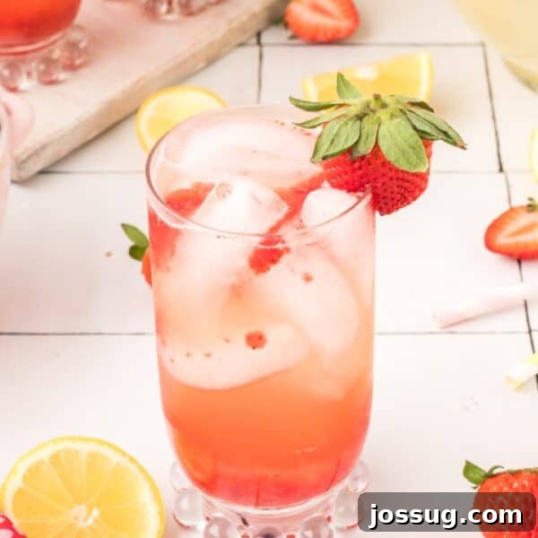 Square image of homemade Freckled Lemonade with fresh strawberry garnish and lemon slices.