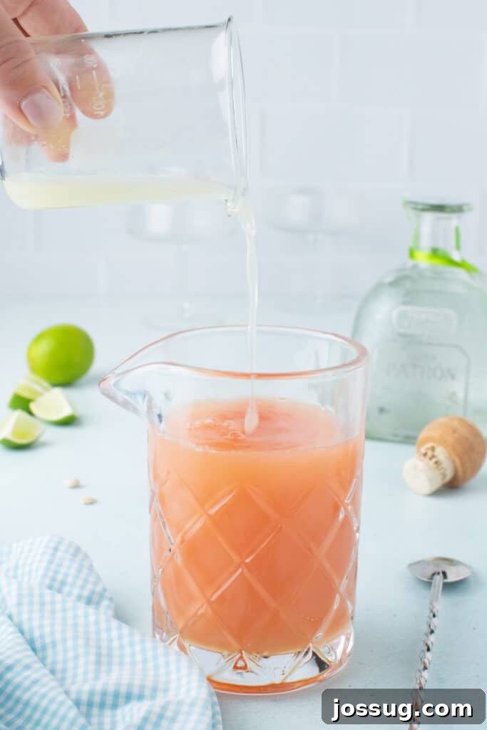 Pouring fresh lime juice into a mixing glass for a homemade Paloma Cocktail.