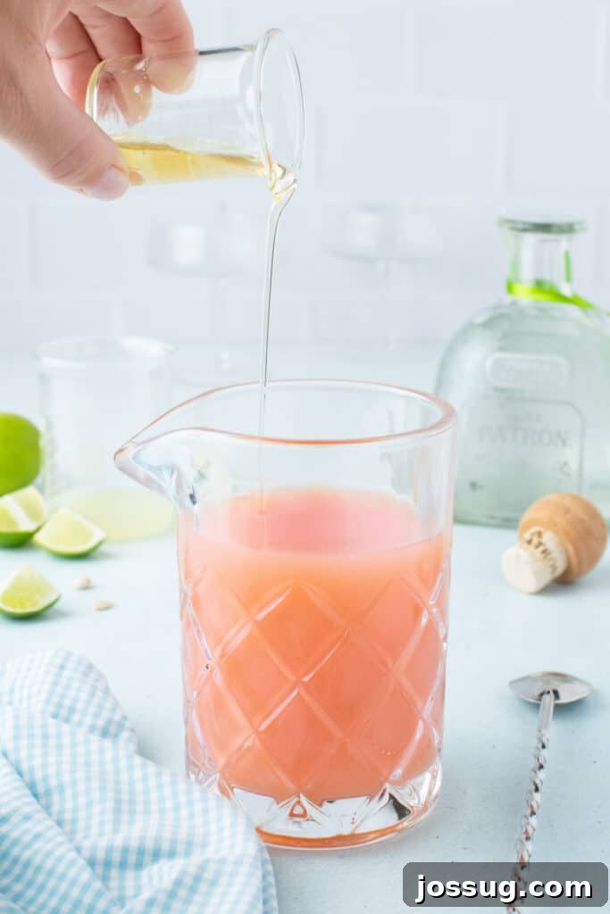 Adding agave syrup to fresh grapefruit juice while making a Paloma Cocktail.