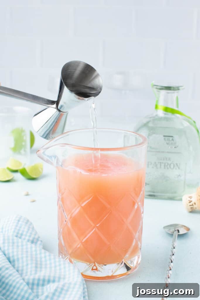 Pouring tequila into a mixing glass with fresh citrus for an easy Paloma Cocktail.