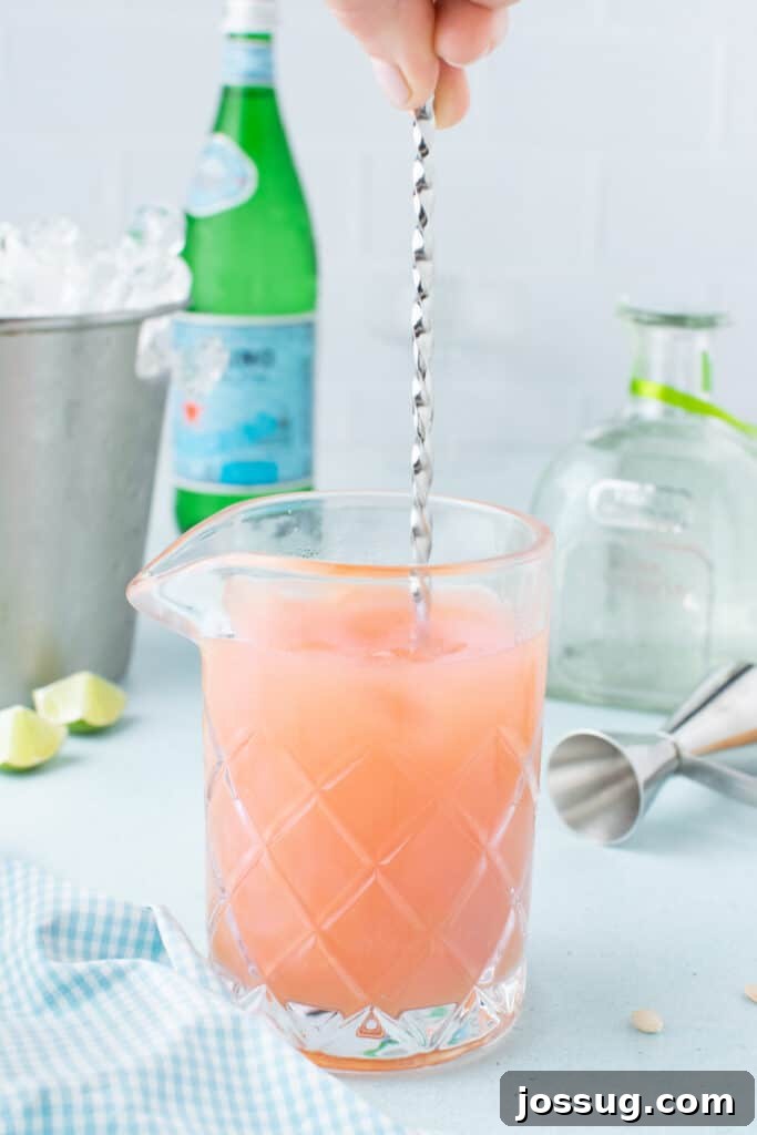 Stirring a homemade Paloma Cocktail with ice before serving.