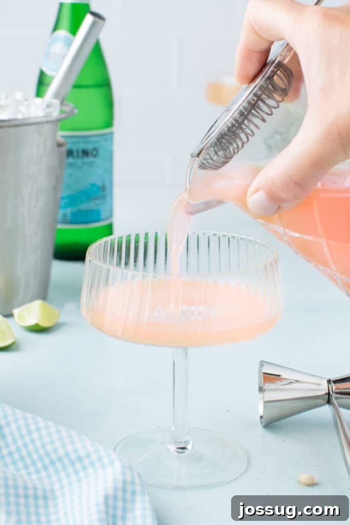 Straining a freshly mixed Paloma Cocktail into a coupe glass.