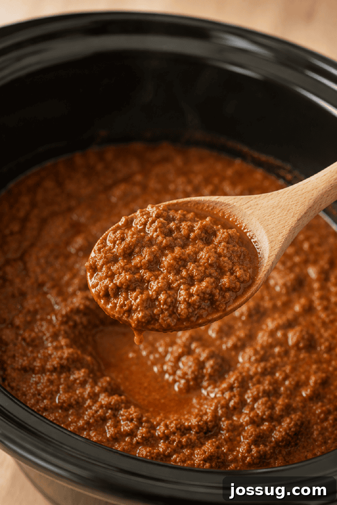 Slow Cooker Hot Dog Chili with Homemade Chili Sauce 8 Spoon lifting Slow Cooker Hot Dog Chili from the crockpot, showing the fine meat texture.