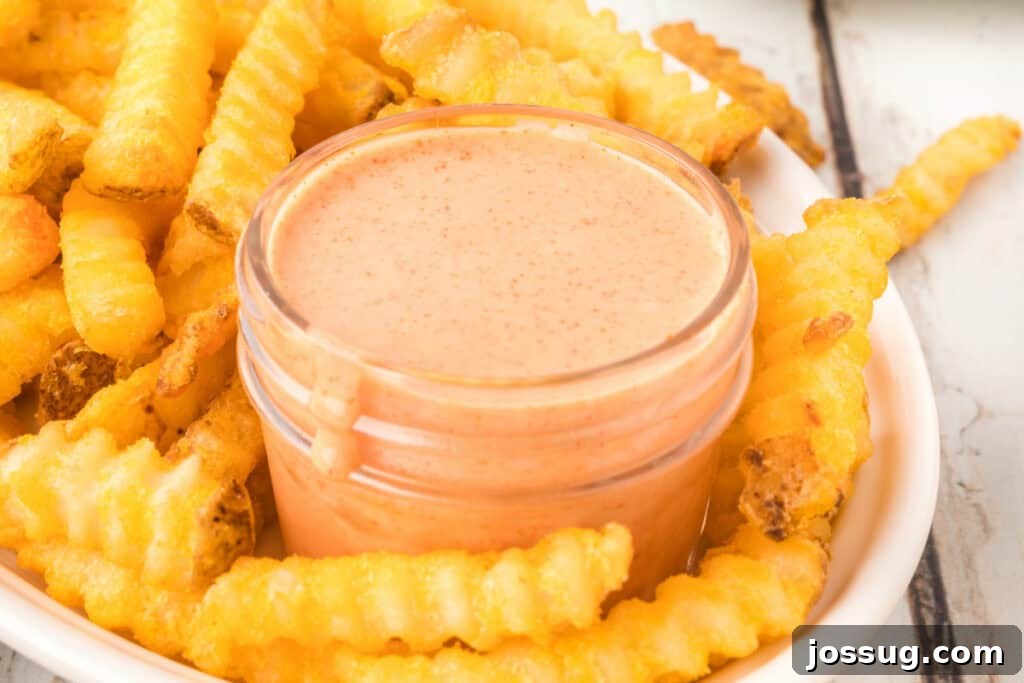 Homemade Fry Sauce Recipe: Tangy Dipping Sauce 4 Close-up of creamy homemade Fry Sauce in a glass jar nestled among crinkle-cut French fries.