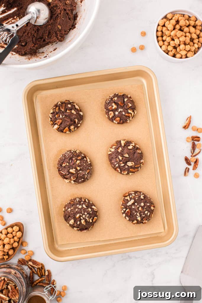 Baked Easy Turtle Cookies on a parchment-lined baking sheet before adding the caramel drizzle.